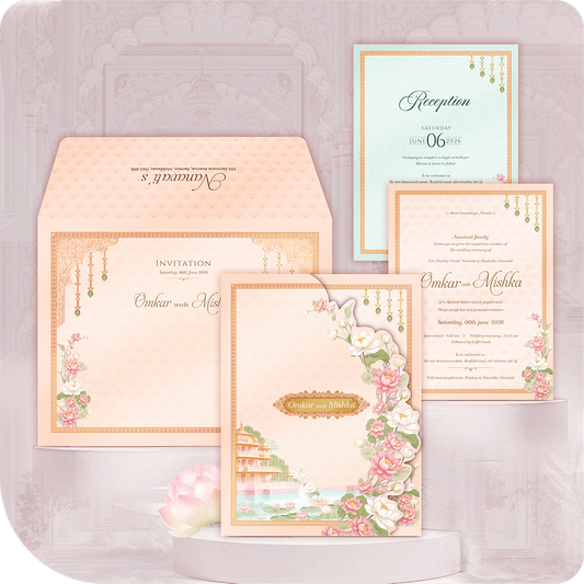 Luxury Udaipur Lakeside Palace Wedding Invitation Card with printing. Destination wedding suite featuring a Pichwai-inspired illustration of a palace and pink lotus flowers in a peach and mint green folder style. Includes Wedding and Reception insert cards and a custom envelope. Premium royal Indian wedding stationery. Full custom printing service included.